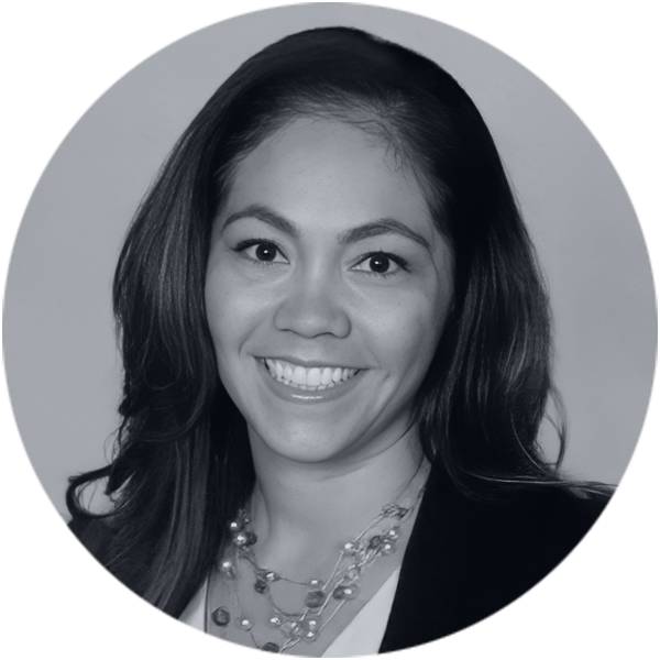 Executive Team Member Professional Headshot Smiling woman with long dark hair, wearing a blazer and a multi-strand necklace, looking confidently at the viewer.